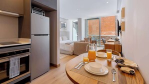 A modern kitchen with a built-in oven and a refrigerator. There is a dining area with a table set for breakfast, including plates, cutlery, and a pitcher of orange juice. - Capitalia | Jacuzzi Upstairs, Car Downstairs (Ciudad de México)