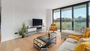A modern living room with a large TV, sofa, and coffee table.