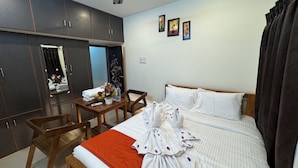 Habitación de hotel con cama, escritorio de madera, silla, armario y tres cuadros en la pared.