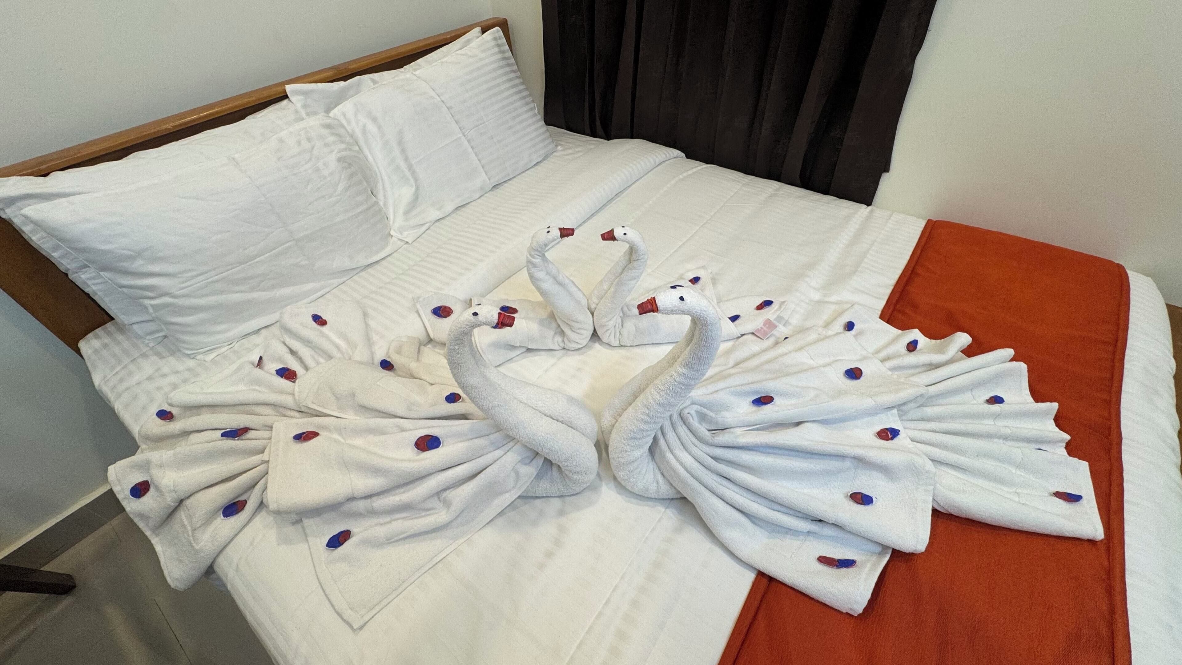 Een bed met witte lakens en handdoeken gevouwen in de vorm van zwanen.