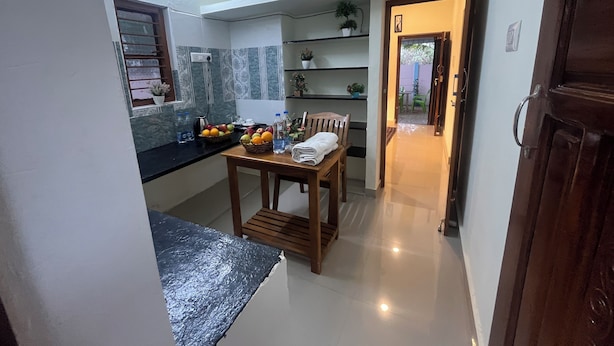 Cocina compacta con mesa, sillas y encimera con cestas de fruta.