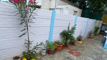 Una hilera de plantas en macetas a lo largo de un muro de ladrillo blanco con detalles verticales azules.