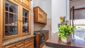 A kitchen with wooden cabinets, a granite countertop, and a potted plant on the island. - Bilo Asfodelo Alghero Centro (Alghero)