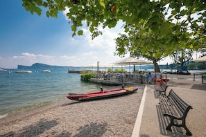 A lakeside setting with a row of benches, a kayak, and a dock with boats.