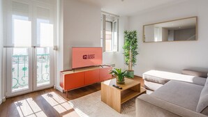 Un soggiorno moderno con una TV a schermo piatto su un supporto in legno, una pianta in vaso, un tavolino in legno e un divano.