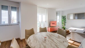 Un soggiorno moderno con un tavolo rotondo in marmo, divani beige e un mobile TV rosso.
