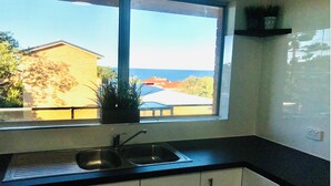 A kitchen with a window, a sink, and cabinets. - Christmas by the Sea - Balcony Ocean View (Port Macquarie)