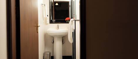 A small bathroom with a white sink, a mirror, and a black and white checkered floor.