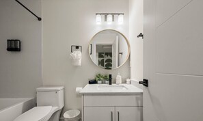 A modern bathroom with a toilet, sink, and mirror. - Studio Verde | Bright & Cozy | 4 min to University (Edmonton)
