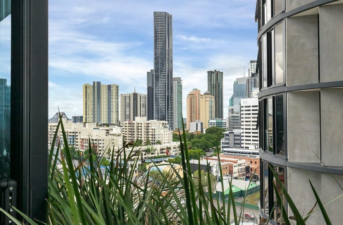 Un paisaje urbano con edificios altos, incluyendo un rascacielos destacado, visto desde una ventana con vistas al paisaje de la ciudad.
