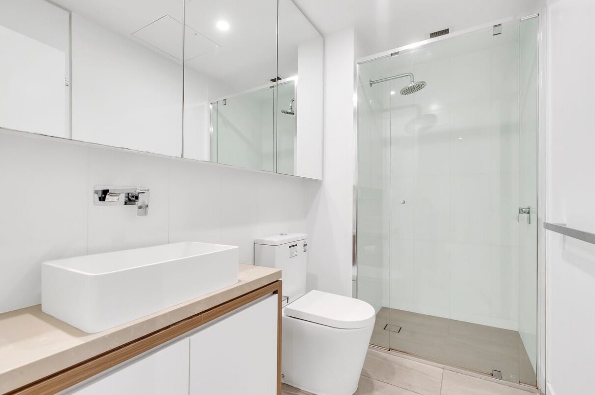 A modern bathroom with a large rectangular sink, a toilet, and a glass-enclosed shower.