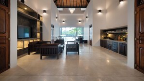 A spacious living area with a high ceiling, built-in entertainment system, and a kitchen with modern appliances.