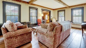 A spacious living room with wooden beams, large windows, and patterned furniture. - All-Season Lakefront Escape 8 Mi to Mount Sunapee (Bradford)