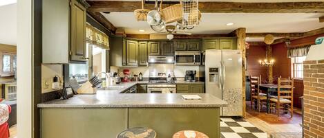 Una cocina con una isla central, taburetes de madera y piso a cuadros.