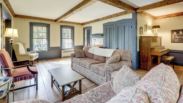 A spacious living room with wooden beams, a patterned sofa, a table, and a piano. - All-Season Lakefront Escape 8 Mi to Mount Sunapee (Bradford)