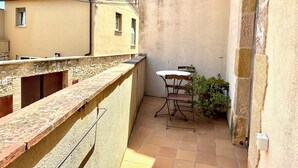 A small outdoor patio with a table and chairs, a stone wall, and a view of neighboring buildings.