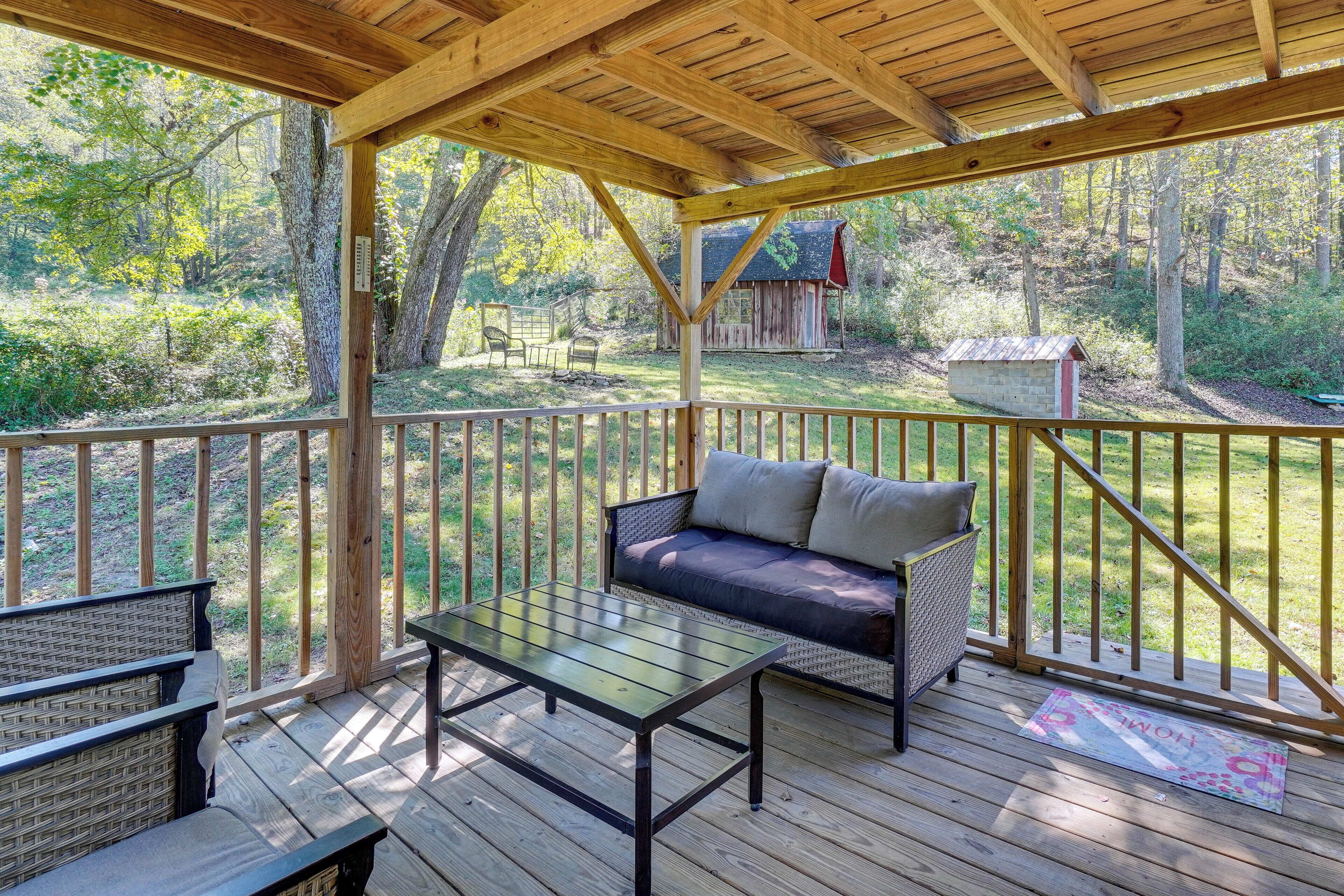 Une terrasse couverte avec un banc en bois, une table et un canapé.