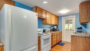 Una cocina con armarios de madera, un refrigerador blanco, una estufa y un microondas.