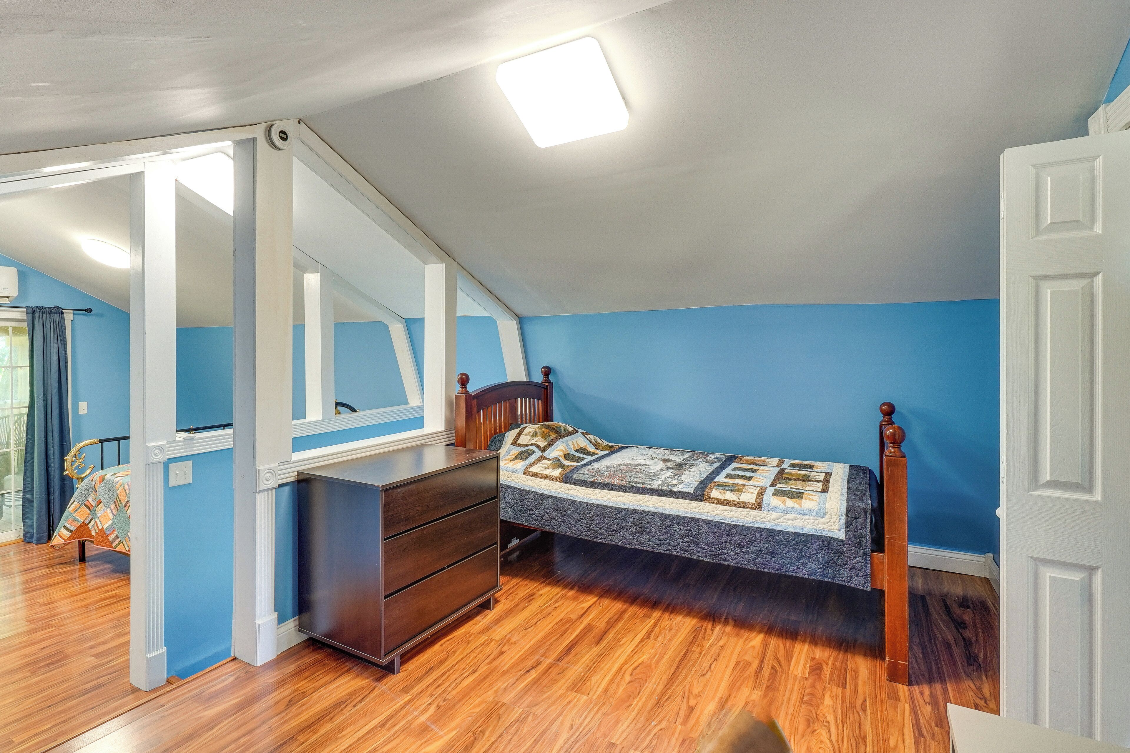 Een slaapkamer met een bed, een ladekast en een spiegel.