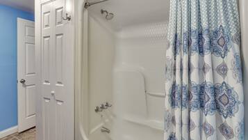 A bathroom with a bathtub, shower, and two white doors.