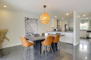 A modern kitchen with white cabinets, a central island, and a dining area with a black table and brown chairs. - Pets Welcome: Beachfront Family Retreat in Norfolk (Norfolk)