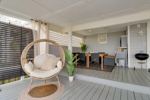 A covered outdoor area with a wicker chair, a small table with chairs, a potted plant, and a barbecue grill. - Pets Welcome: Beachfront Family Retreat in Norfolk (Norfolk)