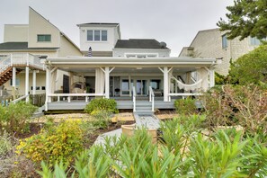 A two-story house with a covered porch, a hammock, and a garden with various plants. - Pets Welcome: Beachfront Family Retreat in Norfolk (Norfolk)