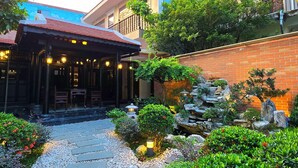 A traditional-style building with a tiled roof and a stone pathway leading to a covered seating area. - Lumiere Villa Hue (Hue)