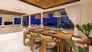 A modern dining area with a wooden table set for six, surrounded by beige chairs. - Villa Aroka 4 Bed Sea View KBR41 (Koh Samui)