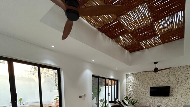 A modern kitchen with a large island, a stone accent wall, and a ceiling fan. - u paradisu villas (Jambiani)