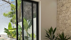A modern interior with a large sliding glass door leading to an outdoor garden area. - u paradisu villas (Jambiani)