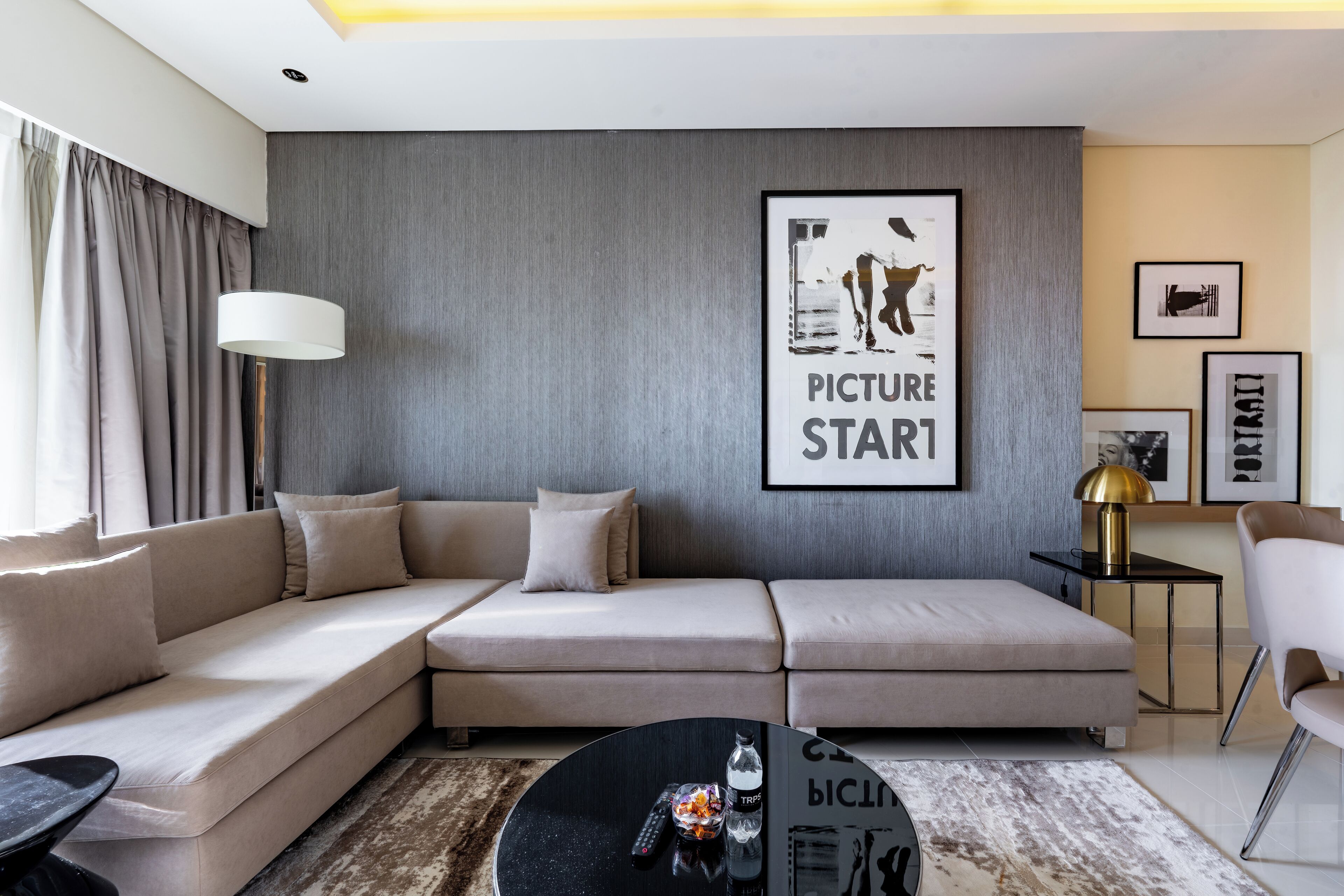 Un salon moderne avec un canapé d’angle, une table basse et un cadre photo fixé au mur.