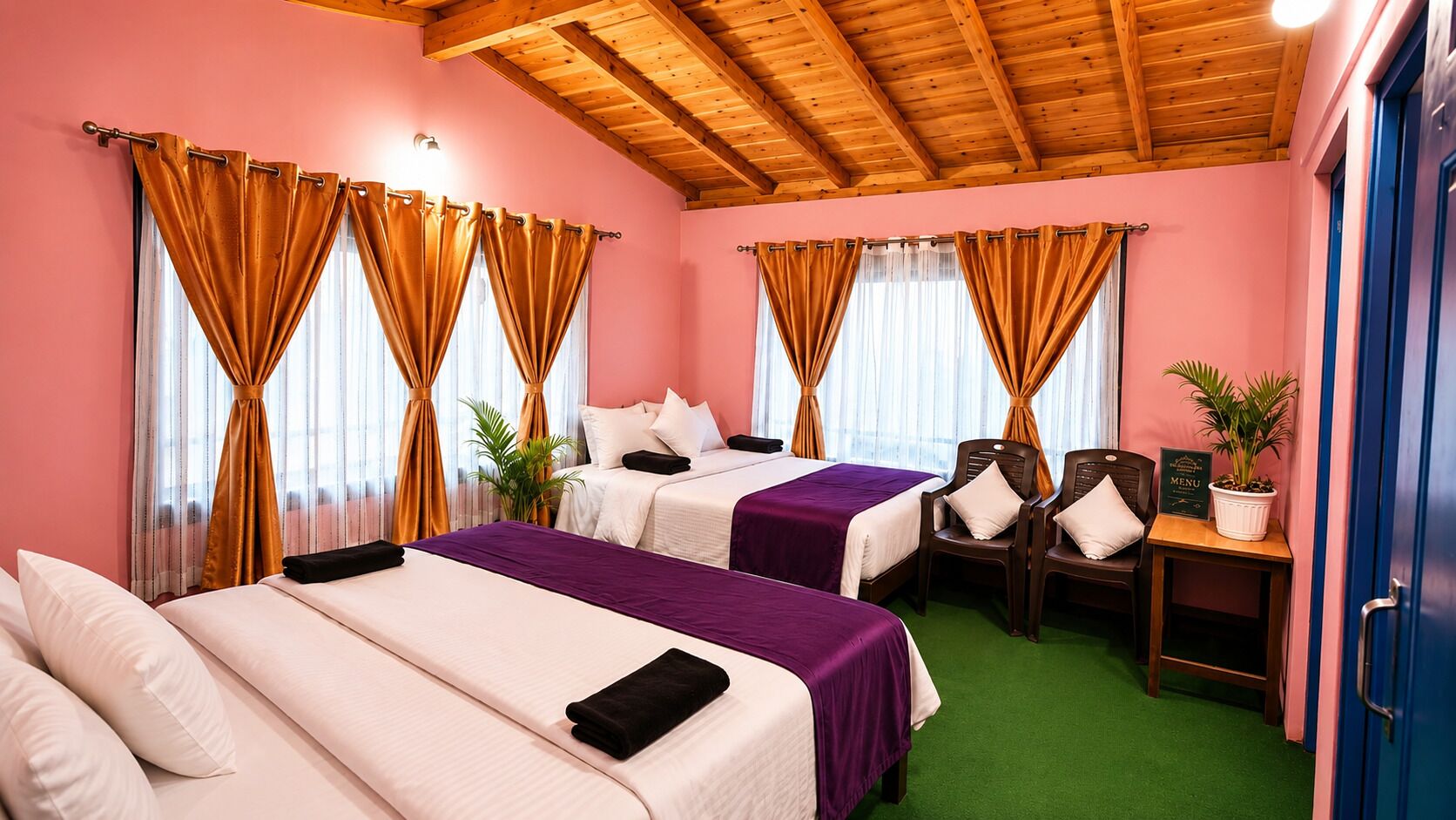 A hotel room with two beds, a desk, chairs, and a small table with a plant.