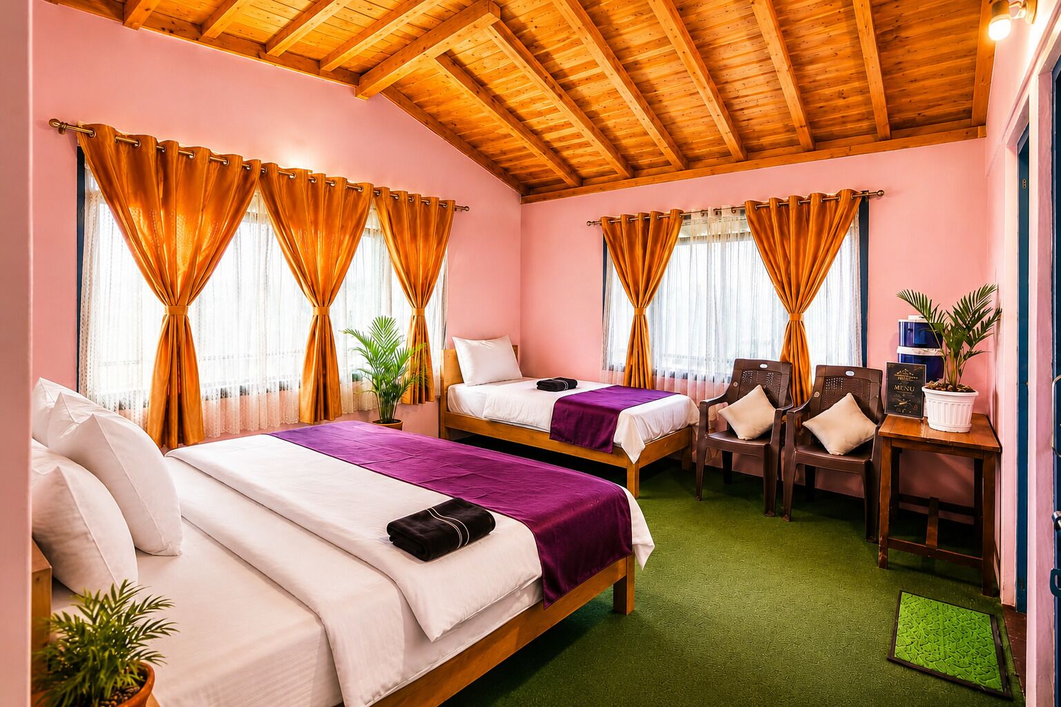 Une chambre d’hôtel avec deux lits, un bureau, des chaises et une moquette verte.