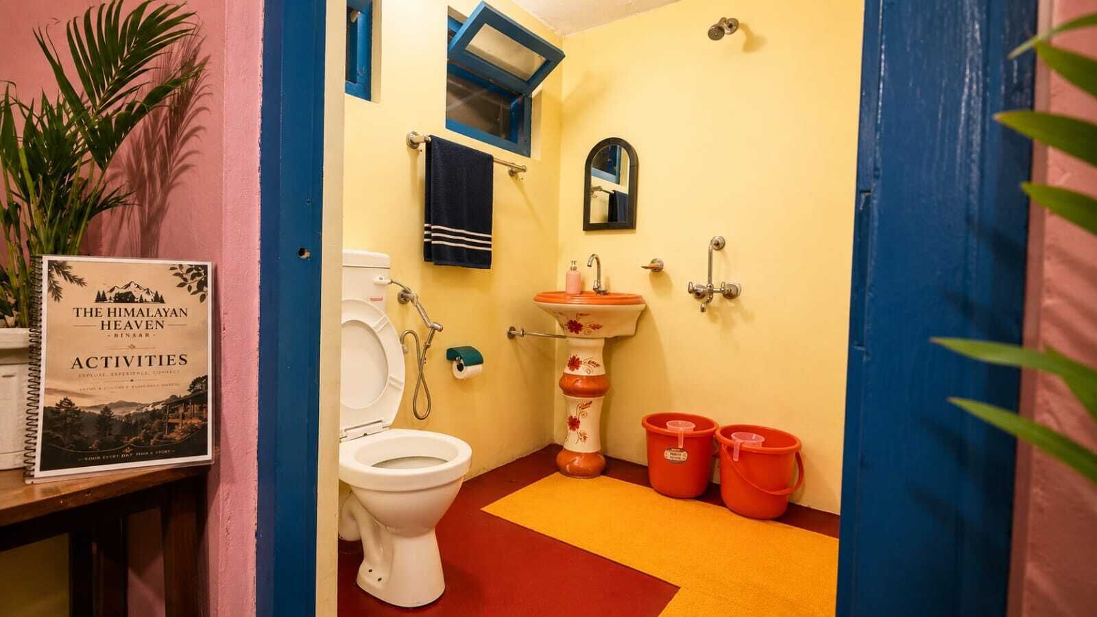 Une salle de bain avec des toilettes, un lavabo et deux seaux rouges.