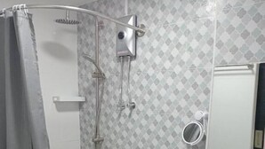 Egy fürdőszoba zuhanyzóval, WC-vel és mosdókagylóval.