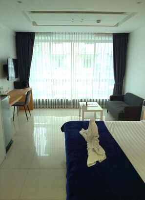 Une chambre d’hôtel équipée d’un lit, d’un bureau, d’une chaise, d’une télévision et d’un canapé.