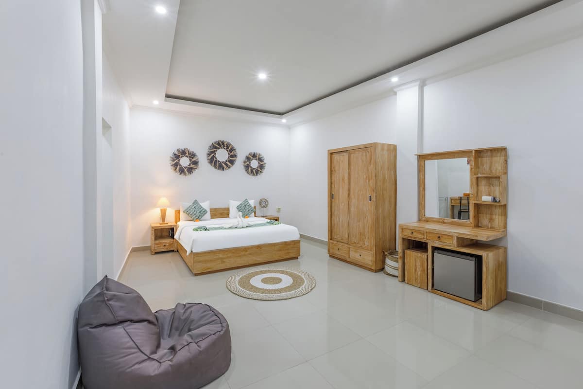 Un dormitorio moderno con cama, armario de madera, mesita de noche y un televisor pequeño.