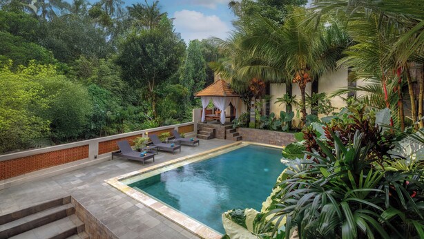 A pool with a tiled deck, lounge chairs, and a small gazebo. - Hanaka Riverside Ubud  (Ubud)