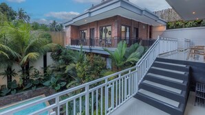 Une maison moderne dotée d’un balcon, d’une piscine et d’une végétation luxuriante.