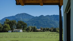 Blick auf ein Gebirge mit einem Haus und einem eingezäunten Feld im Vordergrund.