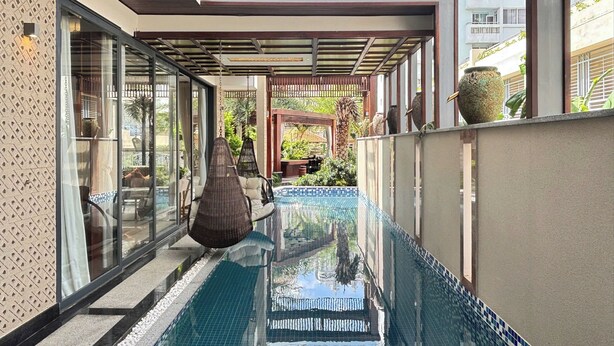 A modern outdoor pool area with a glass enclosure, seating, and a pergola. - Lumiere Villa Nam Thong Phu My Hung (Ho Chi Minh City)