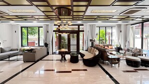 A spacious living area with a modern design, featuring a sofa set, a coffee table, and a dining table. - Lumiere Villa Nam Thong Phu My Hung (Ho Chi Minh City)