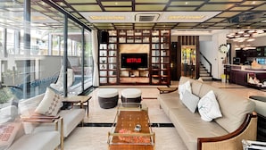 A modern living room with a large TV, comfortable seating, and a view of the outdoors. - Lumiere Villa Nam Thong Phu My Hung (Ho Chi Minh City)