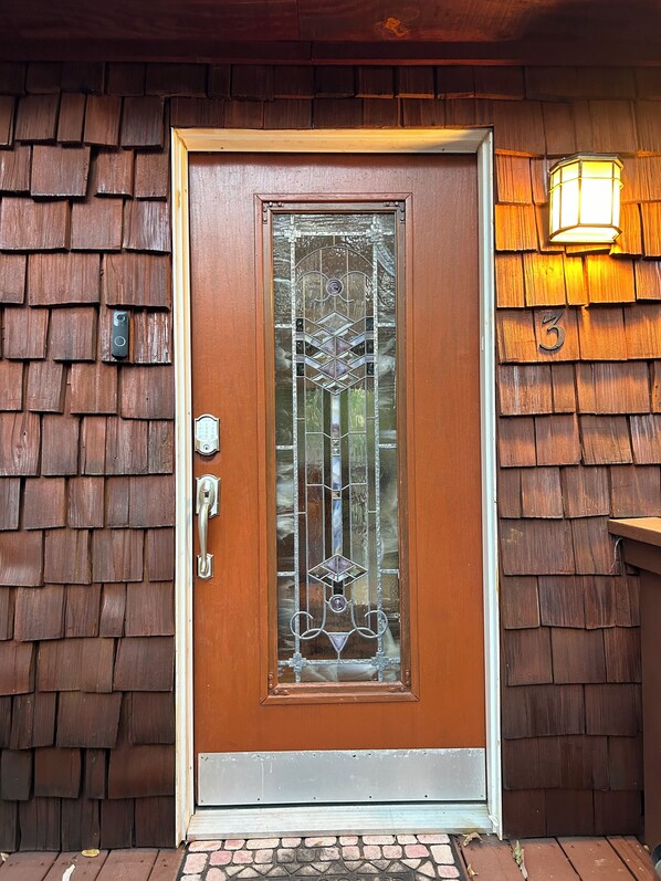 A wooden door with a glass panel and a metal handle, a number '3' sign, and a wall-mounted light fixture.