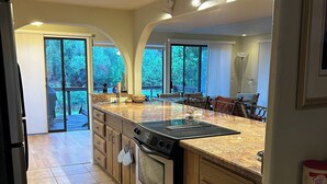A modern kitchen with a large island, built-in oven, and ample natural light from large windows. - 2-bedroom home in Sedona on the creek (Sedona)