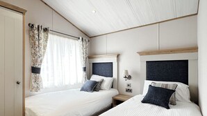 A hotel room with two beds, a wardrobe, a nightstand, and a window with curtains. - 1 bedroom accommodation in Chester (Chester)