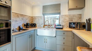 A modern kitchen with a built-in oven, a microwave, a coffee maker, and a sink. - 1 bedroom accommodation in Ripponden (Ripponden)