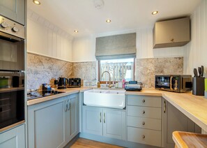 A modern kitchen with a built-in oven, a microwave, a coffee maker, and a sink. - 1 bedroom accommodation in Ripponden (Ripponden)