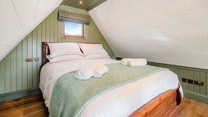 A bedroom with a sloped ceiling, a bed with white linens, a green patterned throw, and a window with a view. - 1 bedroom accommodation in Ripponden (Ripponden)